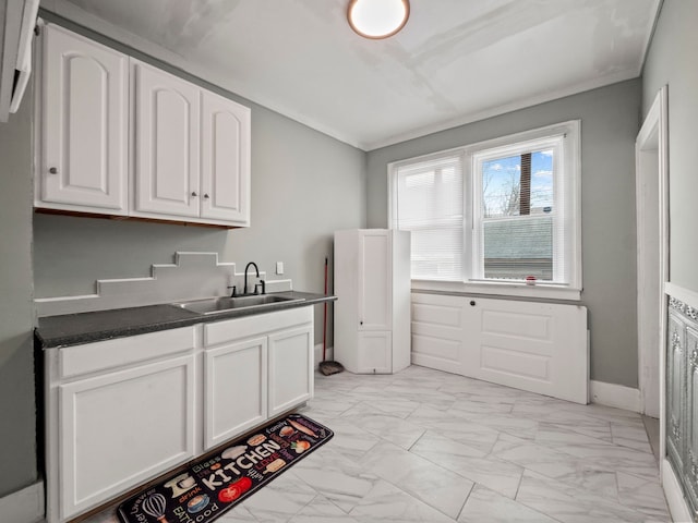 kitchen featuring baseboards, a sink, white cabinetry, dark countertops, and marble finish floor