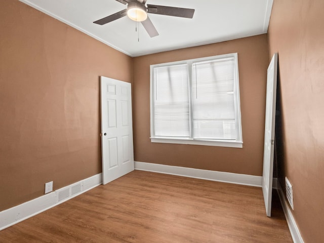 spare room featuring visible vents, baseboards, ceiling fan, and wood finished floors