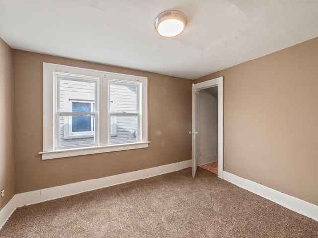 carpeted spare room featuring baseboards