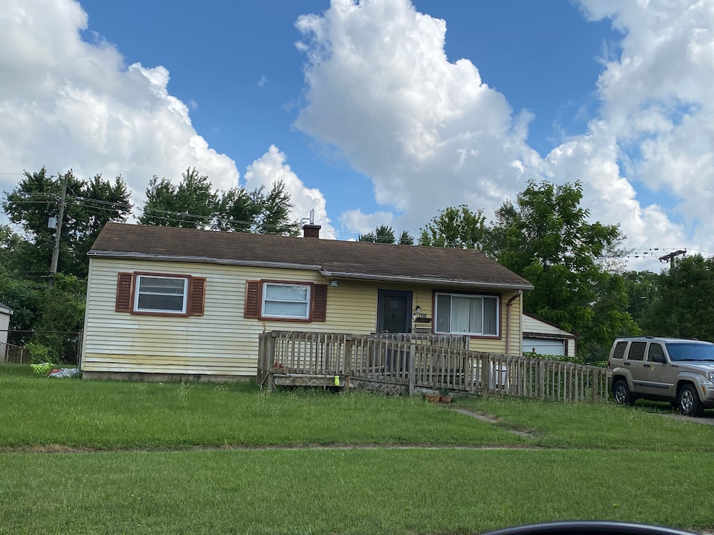 ranch-style home with a front yard, fence, and a chimney