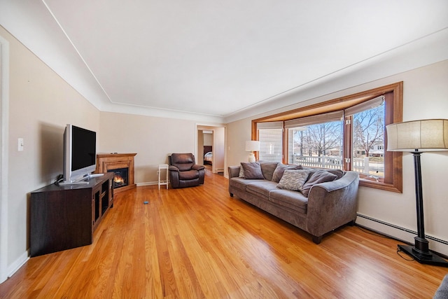 living room featuring light wood-style flooring, baseboards, and a lit fireplace