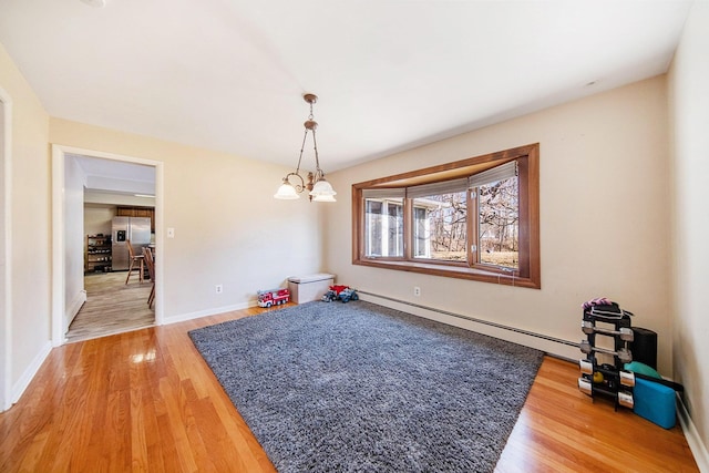 dining space featuring baseboards, light wood-style floors, baseboard heating, and a chandelier