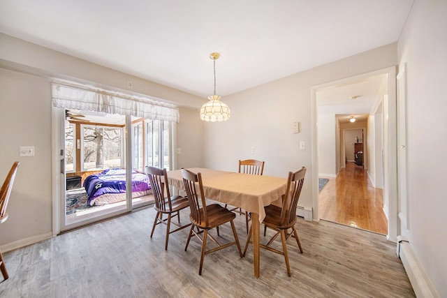 dining room with a chandelier, baseboards, baseboard heating, and light wood-style flooring