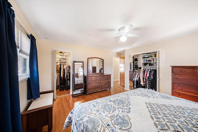 bedroom with light wood-style flooring, a ceiling fan, a closet, baseboards, and a spacious closet