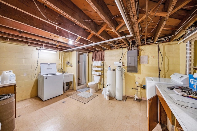 unfinished below grade area featuring washer and clothes dryer, light floors, and electric panel