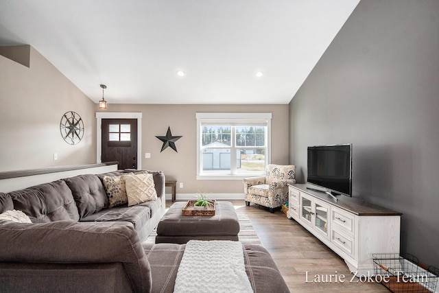 living room featuring plenty of natural light, baseboards, light wood-style floors, and vaulted ceiling