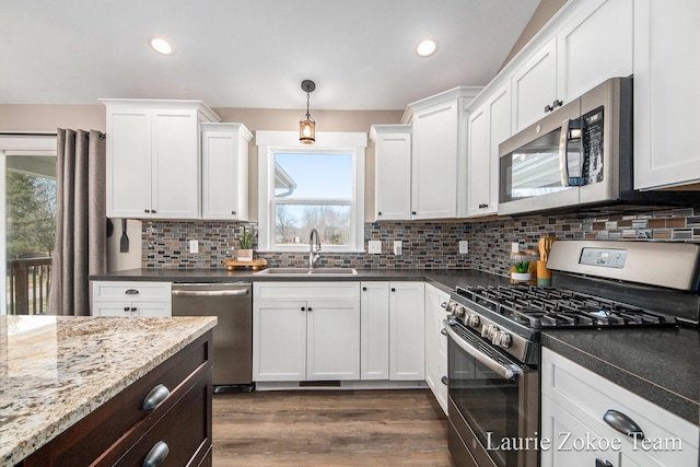 kitchen with decorative backsplash, white cabinetry, stainless steel appliances, and a sink