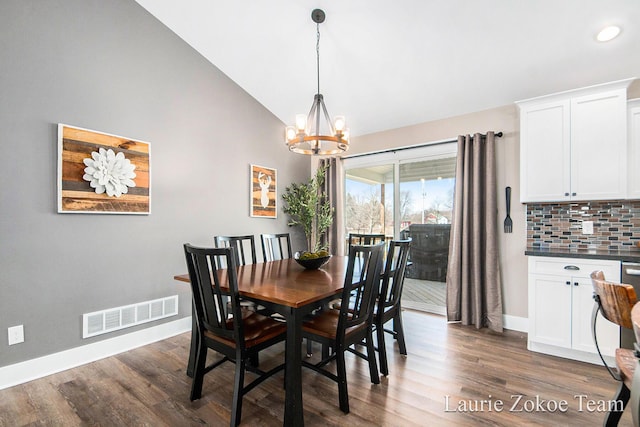 dining space with lofted ceiling, a notable chandelier, dark wood-style floors, and visible vents