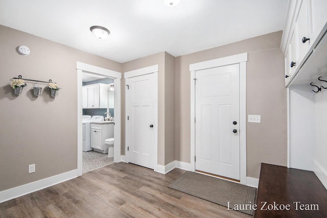 foyer entrance featuring washer and dryer, wood finished floors, and baseboards