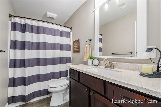 full bath featuring vanity, a shower with shower curtain, wood finished floors, visible vents, and toilet