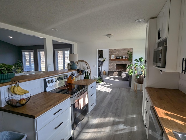 674 Booth Rd, Bronson, MI 49028 - kitchen featuring open floor plan, appliances with stainless steel finishes, white cabinetry, wood finished floors, and butcher block countertops