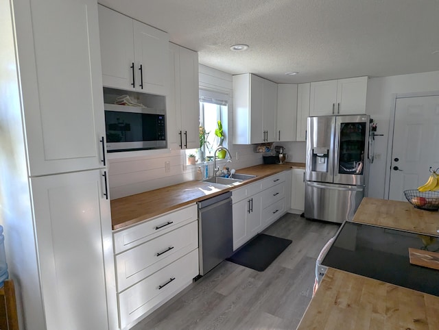 674 Booth Rd, Bronson, MI 49028 - kitchen with light wood-type flooring, white cabinetry, wooden counters, stainless steel appliances, and a sink