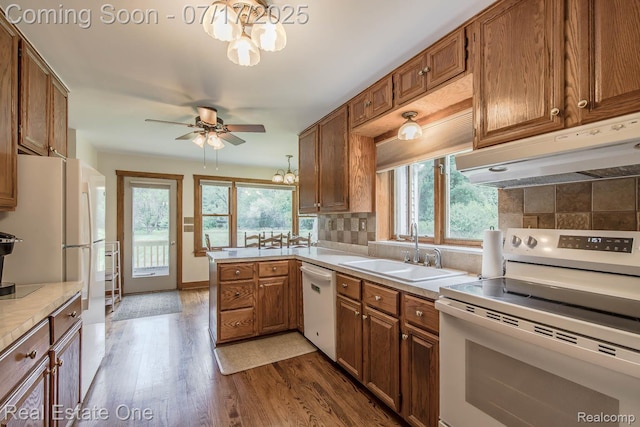 727 Romeo Rd, Rochester, MI 48307 - kitchen featuring white appliances, a chandelier, under cabinet range hood, dark wood-style floors, and decorative backsplash