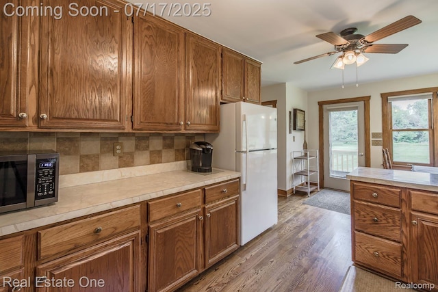 727 Romeo Rd, Rochester, MI 48307 - kitchen featuring brown cabinetry, light countertops, decorative backsplash, freestanding refrigerator, and stainless steel microwave