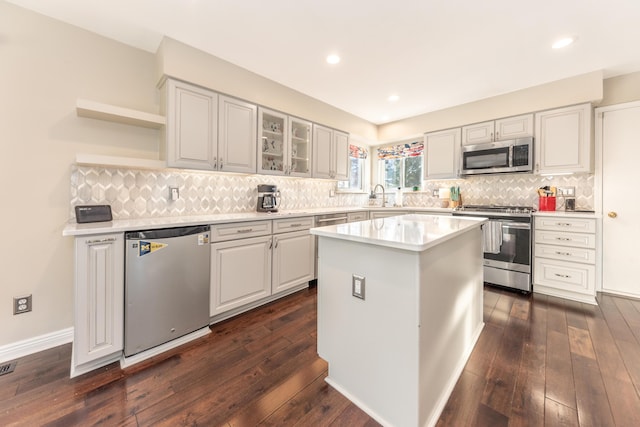 kitchen featuring dark wood-type flooring, a sink, open shelves, appliances with stainless steel finishes, and light countertops