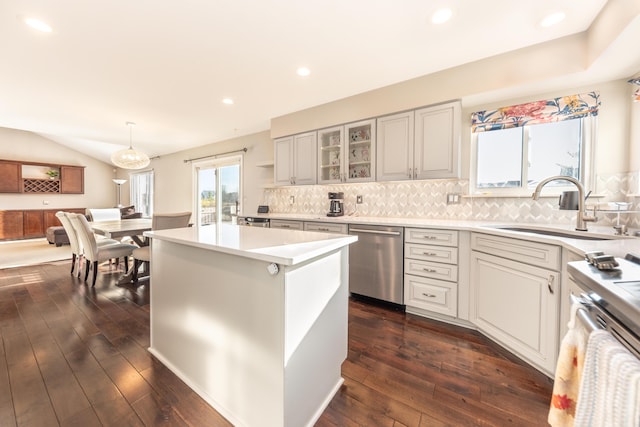 kitchen featuring a kitchen island, dark wood-type flooring, light countertops, stainless steel dishwasher, and a sink