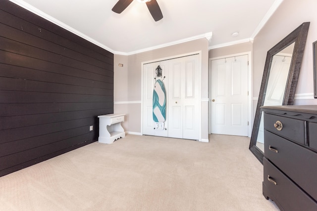 bedroom featuring wooden walls, ceiling fan, a closet, light carpet, and crown molding