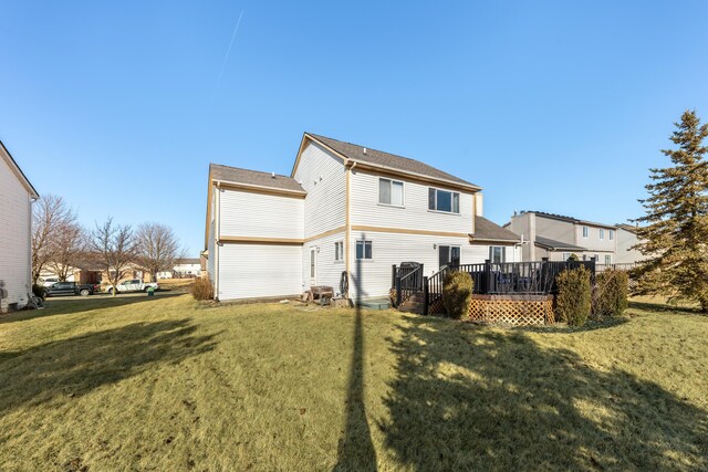 rear view of property featuring a lawn and a deck