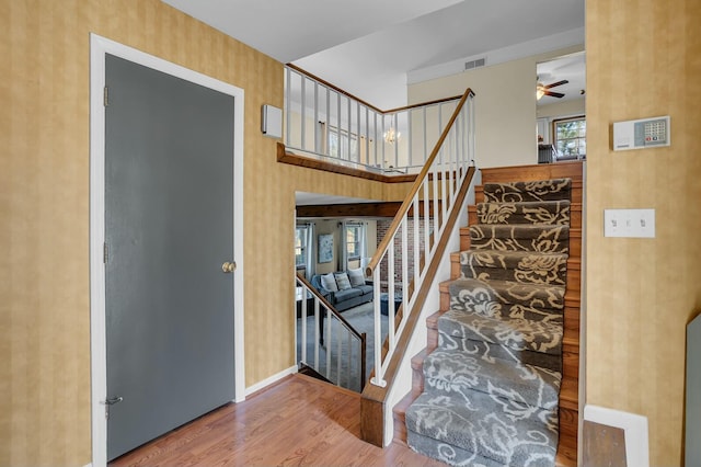 stairs featuring visible vents, wood finished floors, a high ceiling, baseboards, and ceiling fan