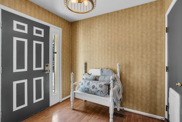 foyer entrance with wallpapered walls, wood finished floors, and baseboards