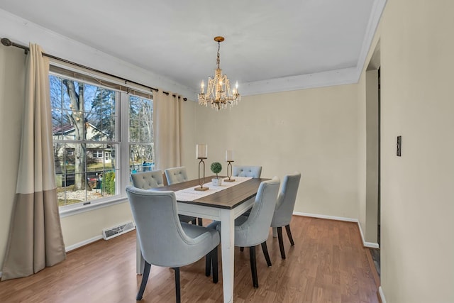 dining room with visible vents, crown molding, baseboards, wood finished floors, and a notable chandelier