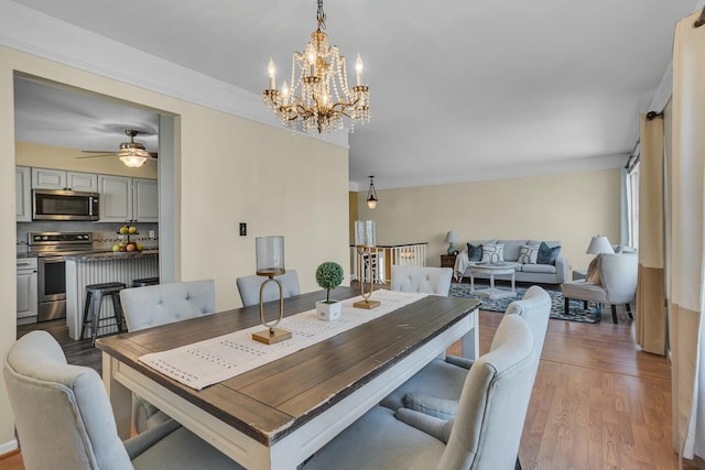 dining space with ceiling fan with notable chandelier and wood finished floors