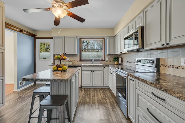 kitchen featuring visible vents, a sink, a kitchen breakfast bar, wood finished floors, and stainless steel appliances