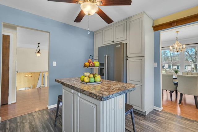 kitchen featuring dark wood finished floors, a kitchen breakfast bar, ceiling fan with notable chandelier, and a kitchen island