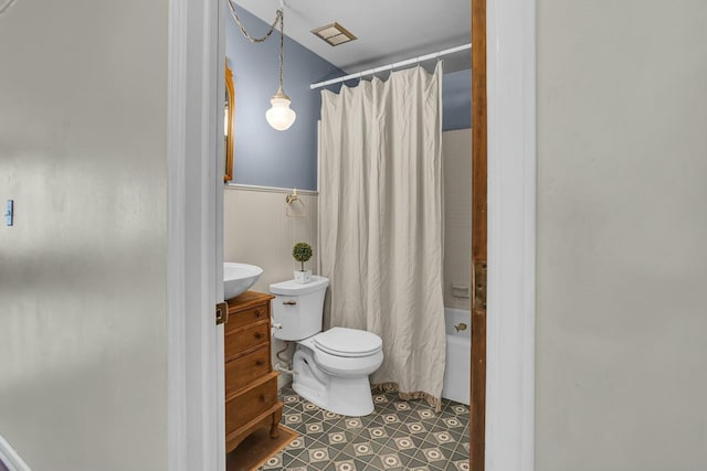 full bath featuring tile patterned flooring, toilet, wainscoting, vanity, and shower / bathtub combination with curtain