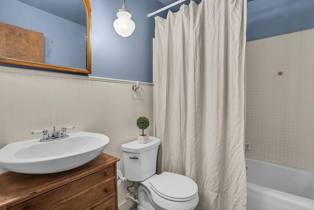 full bath featuring vanity, toilet, shower / bathtub combination with curtain, and wainscoting