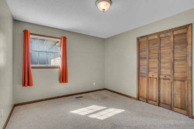 unfurnished bedroom featuring visible vents, baseboards, a textured ceiling, and carpet flooring