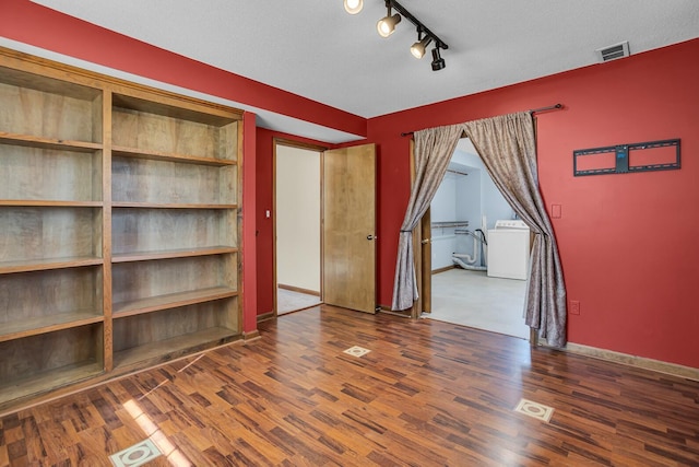 interior space featuring visible vents, baseboards, washer / dryer, and wood finished floors