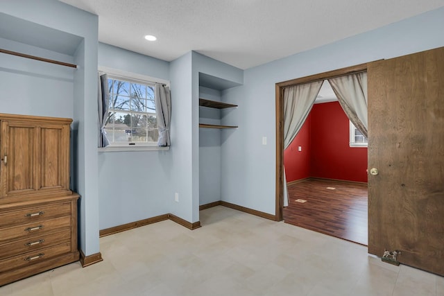 unfurnished bedroom featuring light floors, a textured ceiling, and baseboards