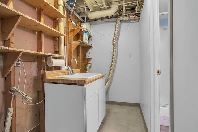 clothes washing area featuring baseboards and a sink