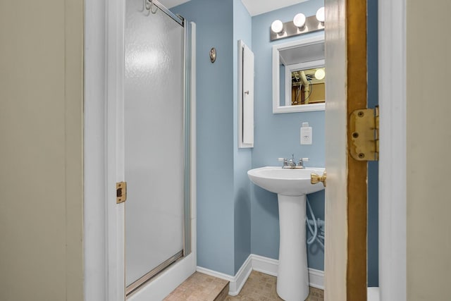 full bath with a sink, baseboards, and a shower stall