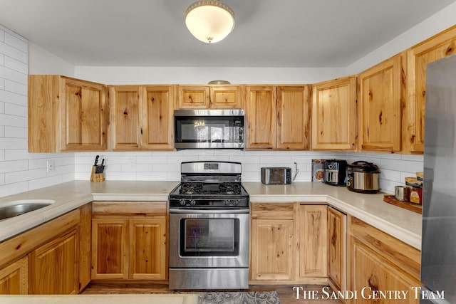 kitchen with backsplash, appliances with stainless steel finishes, and light countertops