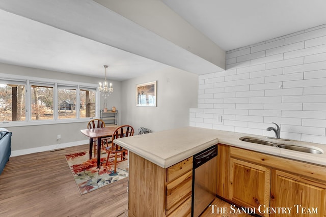 kitchen with a sink, tasteful backsplash, a peninsula, light countertops, and dishwasher