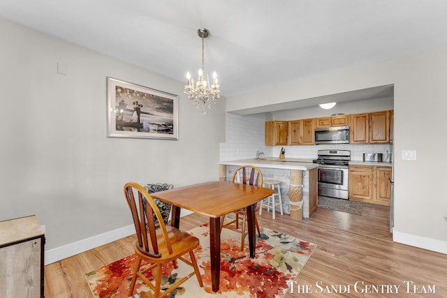 dining area featuring a notable chandelier, baseboards, and light wood-style floors