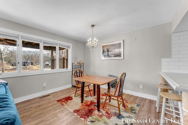 dining space featuring a chandelier, visible vents, baseboards, and wood finished floors