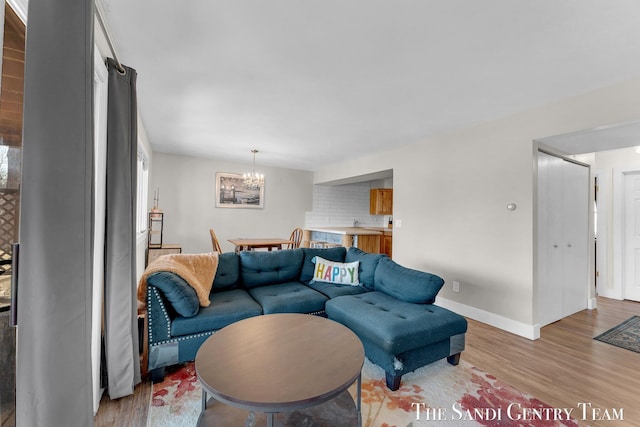 living area featuring baseboards, light wood finished floors, and a chandelier