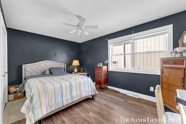 bedroom featuring visible vents, wood finished floors, baseboards, and a textured ceiling