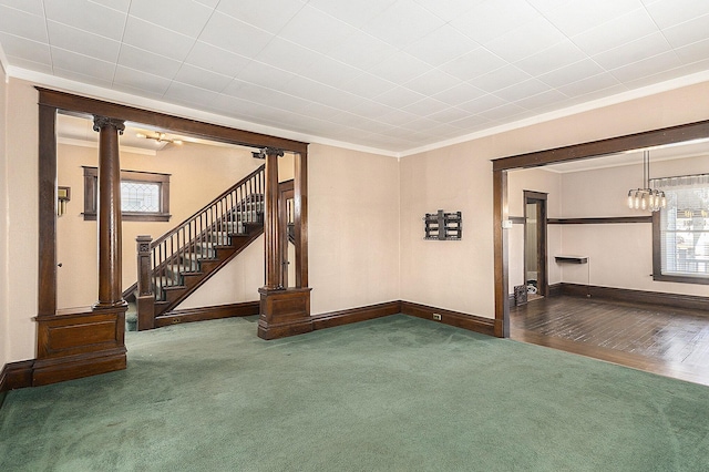 unfurnished living room featuring stairs, crown molding, plenty of natural light, and carpet