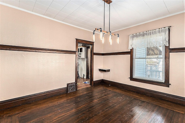 spare room featuring baseboards, dark wood-style flooring, and crown molding