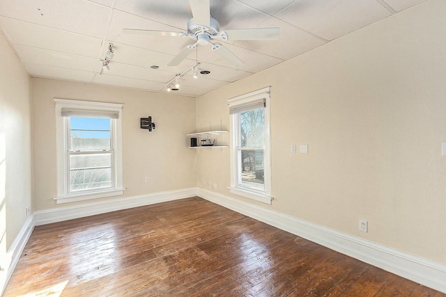 empty room featuring track lighting, baseboards, ceiling fan, and wood-type flooring