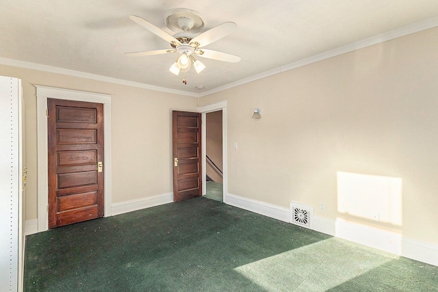 spare room with a ceiling fan, baseboards, visible vents, ornamental molding, and dark carpet