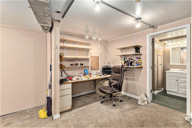 office area with a sink, baseboards, and unfinished concrete floors