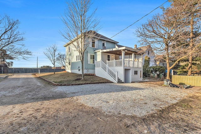 view of front of home with crawl space, stairs, and fence