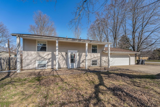 rear view of property featuring concrete driveway, an attached garage, and fence