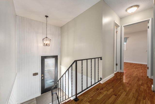 foyer entrance featuring baseboards, a notable chandelier, wood finished floors, and a textured ceiling