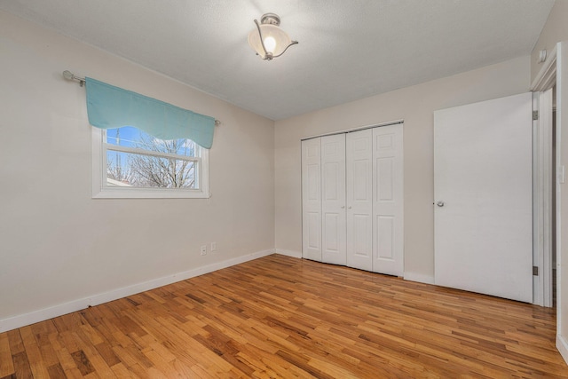 unfurnished bedroom featuring light wood-style flooring, baseboards, and a closet